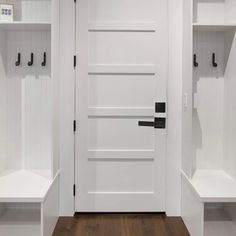 two white shelves with black handles and hooks on them in front of an open door