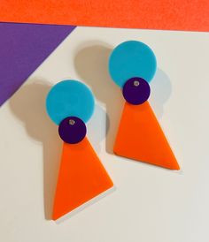 Orange purple turquoise geometric statement earrings. Purple aluminum circles are attached to orange plexiglass and turquoise plexiglass circles using stainless steel micro-screws as cold connections. These colorful statement earrings measure 3 inches in length. Post style for pierced ears. Inspired by abstract art and the Memphis style, my goal is to create art to wear. A mid century design, this colorful brooch will stand out. Wear these with a coordinating bracelet and brooch (see separate listings) for a complete look. 60s Earrings, Cold Connections, 80s Jewelry, Geometric Statement Earrings, Orange Turquoise, Memphis Style, Purple Turquoise, Turquoise And Purple, Earrings Purple