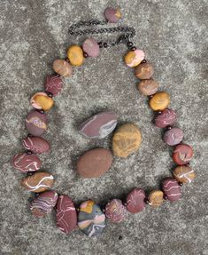 A stunningly unique beach pebble necklace in subtle  but strong shades of burgundy, pink and gold. Twenty four individually crafted polymer clay beads carefully arranged in a balanced combination of colour and shape. 41 cm long, strung on high quality beading wire with a 10 cm extension chain and a softly shining dark burgundy glass seed bead between each pebble. Clay Beaded Necklace, Polymer Clay Beaded Necklace, Clay Bead Necklace, Pebble Necklace, Shades Of Burgundy, Unique Beach, Twenty Four, Dark Burgundy, Beading Wire