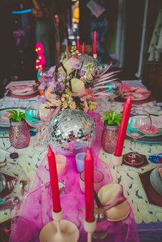 the table is set with pink candles and plates