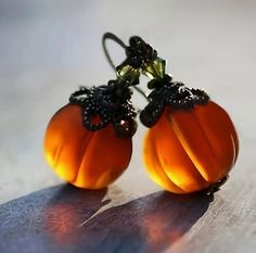 two small orange pumpkins are sitting on a piece of paper with some black beads