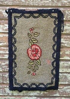 an old rug hanging on the side of a wooden building with a flower embroidered on it