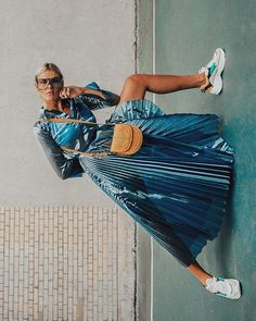 a woman leaning against a wall with her legs spread out and holding a tennis racquet