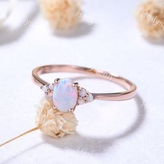 a white opal ring with three stones on it and a flower in the middle