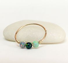 three opalite beads are attached to a gold ring on top of a rock