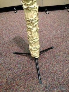 an umbrella that has been wrapped in gold paper and is sitting on the floor next to some black poles