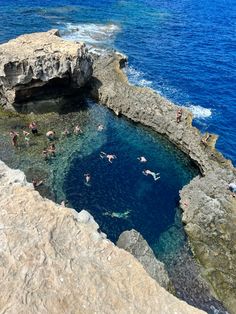 people swimming in the water near some rocks