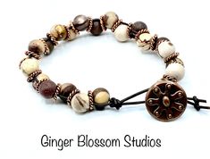 This is a handcrafted cream, brown and copper bracelet fashioned onto a dark brown leather cord. The leather is hand knotted on one end for the closure loop. A antique copper button was chosen for the closure. The bracelet is 7 1/2 inches in length and 1/2 inch wide. This bracelet will stack beautifully with other bracelets.  Thank you for visiting our shop! Artisan Brown Bracelets For Jewelry Making, Brown Copper Bracelets With Round Beads, Unique Hand Wrapped Brown Beaded Bracelets, Unique Brown Wrap Bracelet With Round Beads, Bohemian Brown Beaded Copper Bracelets, Bohemian Brown Copper Beaded Bracelets, Unique Hand Wrapped Brown Wrap Bracelet, Rustic Brown Hand Wrapped Beaded Bracelets, Rustic Brown Hand-wrapped Beaded Bracelets