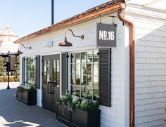 a white building with black shutters on the front and windows that say no16