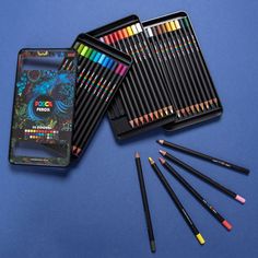 several different colored pencils in tins on a blue surface with one box full of them