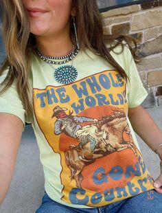 "Gear up for a wild ride with \"The Whole World's Gone Country\" Western Graphic Tee, starring a cowboy on horseback. This tee isn't just clothing; it's a statement. Embrace the rugged charm of the West with a design that captures the spirit of the Wild West." Vintage Summer T-shirt For Rodeo, Spring Graphic Print T-shirt For Rodeo, Fitted Graphic Print T-shirt For Rodeo, Western Style Screen Print Tops For Summer, Retro T-shirt For Western-themed Summer Events, Retro Summer T-shirt For Western-themed Events, Spring Letter Print T-shirt For Rodeo, Graphic Tee Tops For Ranch, Rodeo Screen Print Crew Neck Top