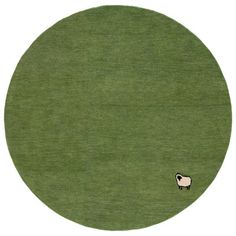 a sheep is standing in the middle of a green field with a white circle behind it