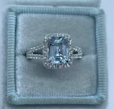 an engagement ring in a box with a blue diamond center stone on the band and two rows of diamonds surrounding it