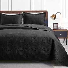 a bed with black bedspread and pillows