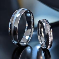 two wedding rings sitting on top of a black table next to each other with diamonds in them