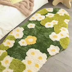 a green and white rug with flowers on the floor next to a teddy bear in a bedroom