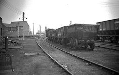 an old black and white photo of train cars on the tracks in front of buildings