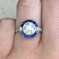 a woman's hand with a diamond and blue sapphire ring