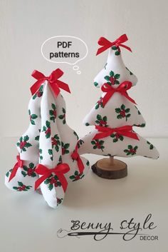 two white christmas trees with red bows and green leaves on them, sitting next to each other