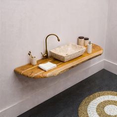 a bathroom sink sitting on top of a wooden shelf next to a rug and toilet paper