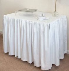 a white table topped with a laptop computer next to a lamp on top of a hard wood floor