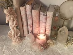 a table topped with lots of books next to a candle and some glass vases