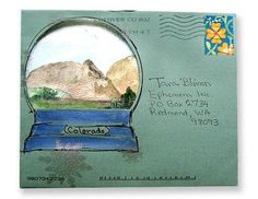 an envelope with a drawing of a snow globe and mountains in the background, as well as a postage stamp