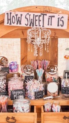 a wooden table topped with lots of candies and candy bar items next to a sign that says how sweet it is