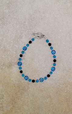 "one of a kind evil eye bracelet, cute evil eye bracelet for teens, blue crystal jewelry Sterling Silver, Glass and Glass Crystal Handmade beaded Bracelet, 7.\".  Round 2mm beads are sterling silver, 4mm bicone beads are glass crystal aquamarine and opaque black. Evil eye beads are flat coin shape 5mm glass. toggle clasp is pewter. evil eye jewelry is designed to protect the wearer from evil and ward off the evil that has been directed at them. Wearing any piece of jewelry with the evil eye symbol on it provides the wearer with both power and protection against evil spirits or bad luck. Check out my other jewelry at https://loveofjewelryshop.etsy.com" Turquoise Bracelets With Evil Eye Round Beads, Turquoise Evil Eye Bracelet As Gift, Adjustable Blue Evil Eye Bracelet Nickel Free, Adjustable Blue Evil Eye Bracelet, Nickel Free, Adjustable Turquoise Evil Eye Bracelet, Adjustable Nickel-free Blue Evil Eye Bracelet, Spiritual Blue Evil Eye Bracelet, Blue Evil Eye Round Bracelets, Blue Round Evil Eye Bracelets