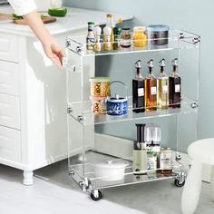 a clear shelf with lots of bottles on it in a room next to a white chair