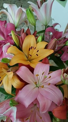 a vase filled with lots of pink and yellow flowers