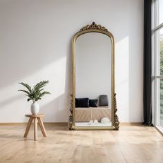 a large mirror sitting on top of a wooden floor next to a vase filled with flowers