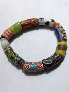 "This colorful bracelet is handmade from recycled glass, formed into beads known as Krobo beads, hand painted, and fired in a kiln in Ghana, West Africa.  The bracelet is 7 1/2\" and is strung on 2mm white elastic cord. It features hand-painted African designed glass beads. Other sizes may be ordered as well as earrings and other jewelry. Just contact us.  All proceeds from the sale of this jewelry go to our non-profit organization Mawuvio's Outreach Programme, which is providing free education and care for orphaned and disadvantaged children in Ghana. The money is used to support a 6 classroom and 2 dormitory school that provides over 200 children with the tool they need to succeed - Education. Students & staff at Mawuvio's Outreach Programme string the beads themselves to create handmade Adjustable Recycled Glass Beads With Large Beads, Artistic Adjustable Beaded Bracelets, Colorful Recycled Glass Beaded Bracelets, Artisan Multicolor Beaded Stretch Bracelet, Colorful Recycled Glass Beaded Bracelets As Gift, Colorful Recycled Glass Beaded Bracelets For Gift, Adjustable Multicolor Beaded Bracelets In Wearable Art Style, Artisan Multicolor Round Beads Stretch Bracelet, Handmade Multicolor Recycled Glass Beads