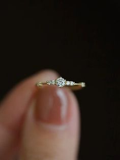 a person holding a ring in their left hand, with the diamond on it's side