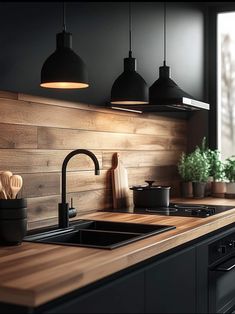 a kitchen with wooden counter tops and hanging lights over the sink, along with potted plants