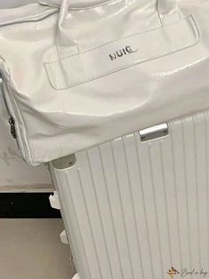 a white suitcase sitting on top of a floor next to a bag with the word tumi written on it