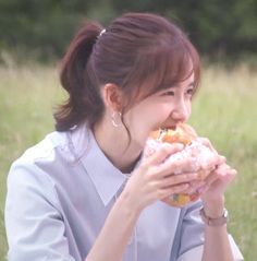 a woman sitting in the grass eating a sandwich