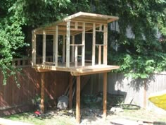 a tree house built into the side of a fenced in area with trees around it