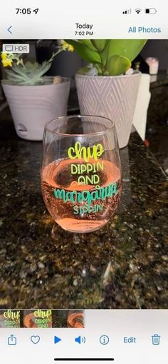 a wine glass sitting on top of a counter next to a potted green plant