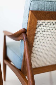 a close up of a wooden chair with blue fabric on the back and armrests