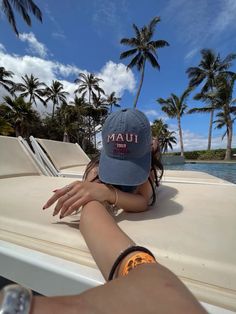 a woman laying on top of a boat near palm trees