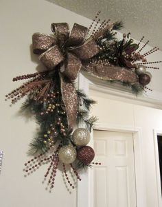 a christmas wreath hanging on the wall above a door with ornaments and decorations around it