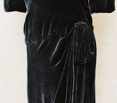 "This silk velvet dress has a dropped, asymmetrical waistline and resembles the styles of about 1930, but was made later (probably the '80's). The color is black, but with a greyish-blue cast when light plays over the surface. The skirt overlaps in front with the top portion curved and drawn up on the side and gathered, with a little pleated piece that drapes down over the skirt. There's a deep V in back and a bow with long streamers. The dress has shoulder pads, is fully lined, and has a center Vintage Velvet Dress For Evening, Vintage Velvet Dress For Night Out, Vintage Black Velvet Dress For Evening, Dropped Waist Dress, Dress With Low Back, Silk Velvet Dress, Bethlehem Pa, Greyish Blue, Dropwaist Dress