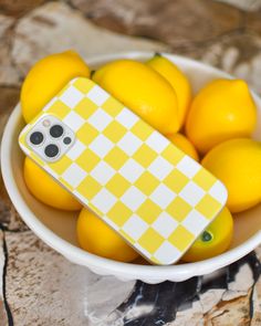 a bowl filled with lemons and a cell phone case sitting on top of it