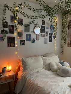 an unmade bed with white sheets, pillows and plants on the wall above it