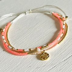 two bracelets with charms on them sitting on a white table next to each other