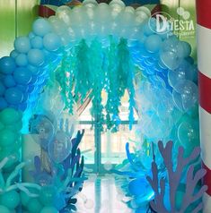 the balloon arch is decorated with blue, green and white balloons that look like corals