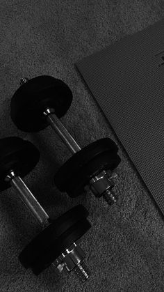 two black dumbbells sitting on the floor next to a yoga mat