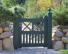 an open gate in front of some rocks and trees