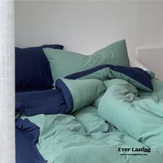 an unmade bed with blue and green pillows